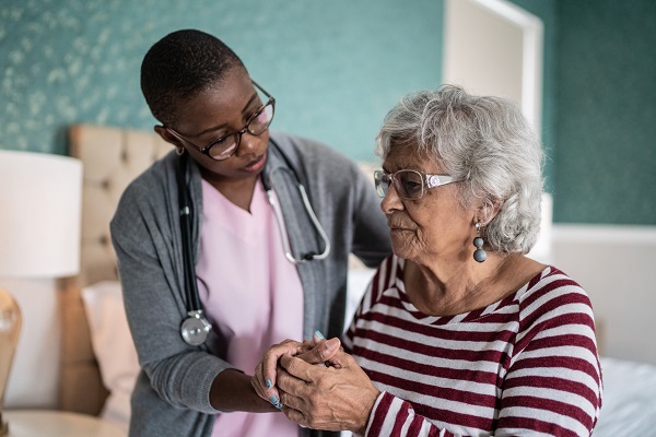 Home caregiver helping a senior woman standing in the bedroom